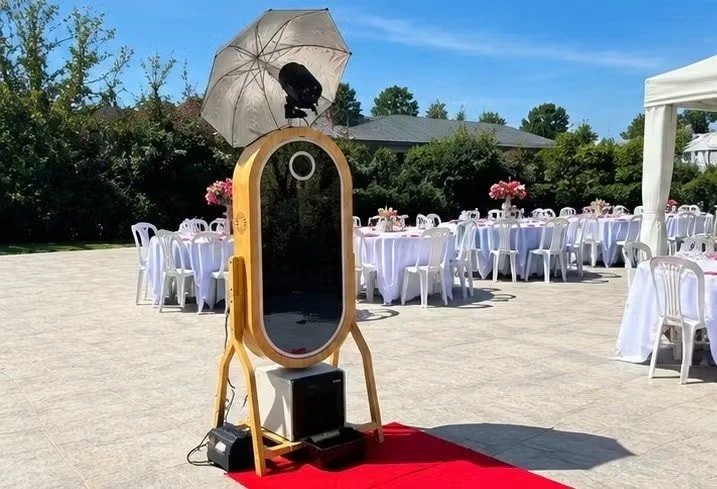 Le miroir photo sur un tapis rouge, devant les tables d’une réception en jardin